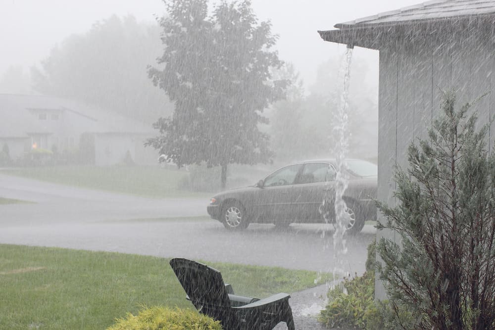 Downspout carrying heavy rain from a roof edge