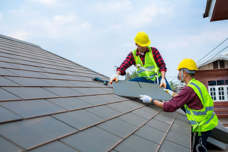 Roofing crew installing shingles under clear sky